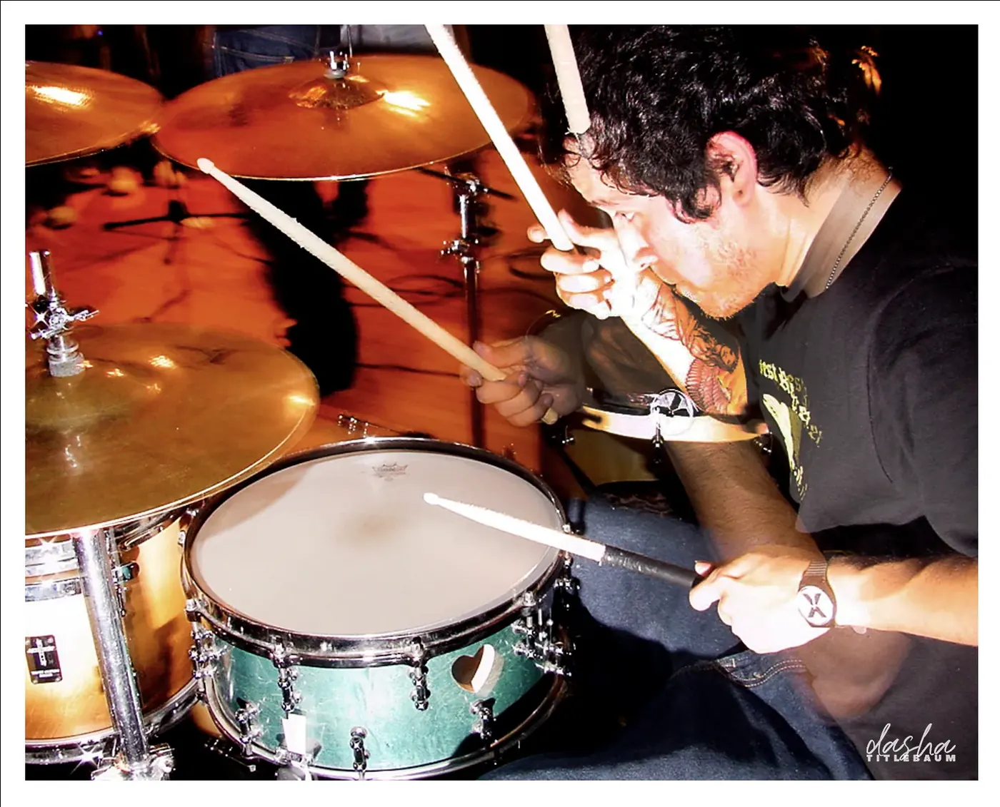 Amity Drummer, Drummer caught mid-strike, freezing motion in low, high-contrast stage light.